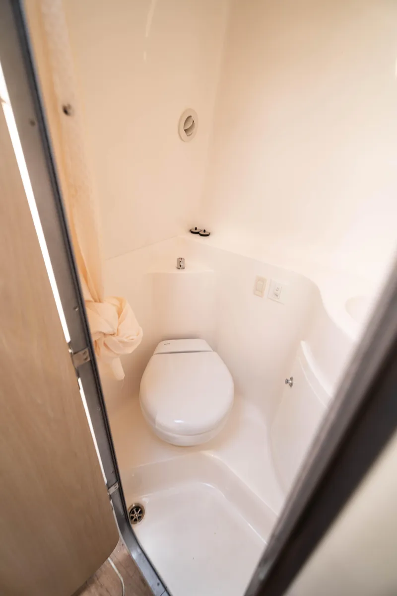 Slide: The Image of 2023 Regal 26 XO boat bathroom with compact toilet and white interior. - 12