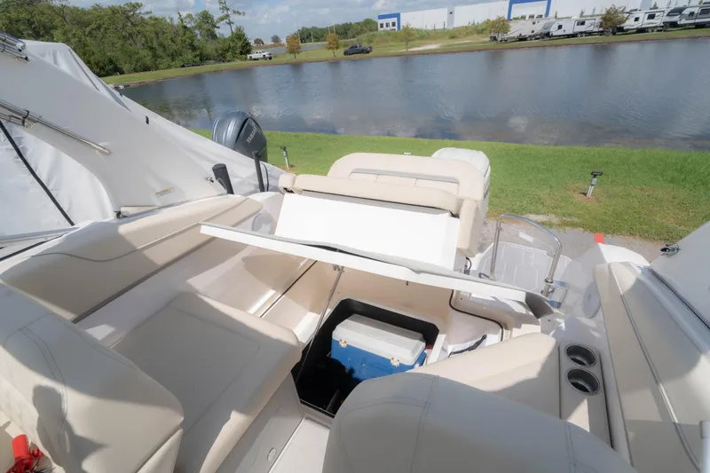 Slide: The Image of 2023 Regal 26 XO boat interior with seating and storage by a lake. - 14