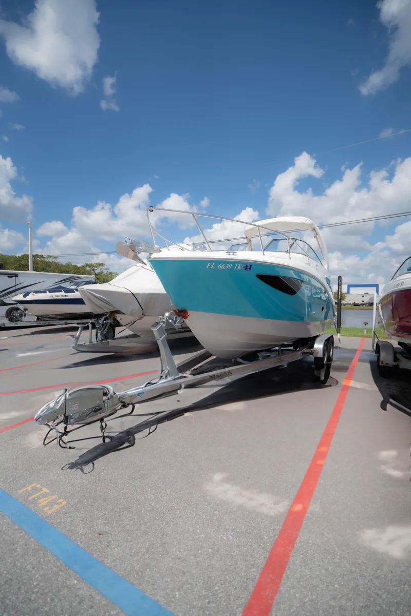 Slide: The Image of 2023 Regal 26 XO boat on trailer under clear blue sky. - 2