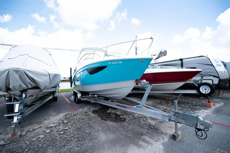 Slide: The Image of 2023 Regal 26 XO boat on trailer, vibrant blue hull, parked outdoors. - 4