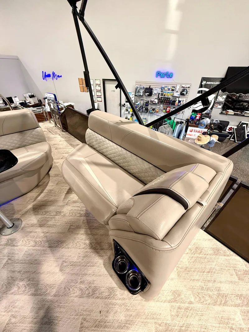 Slide: The Image of 2019 Manitou 25 SES Platinum boat interior with beige seating and cup holders. - 11