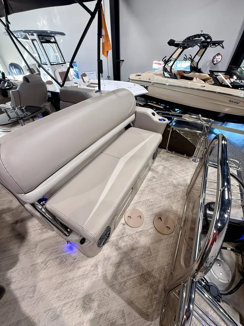 Slide: The Image of 2019 Manitou 25 SES Platinum boat interior with beige seating and modern design. - 16