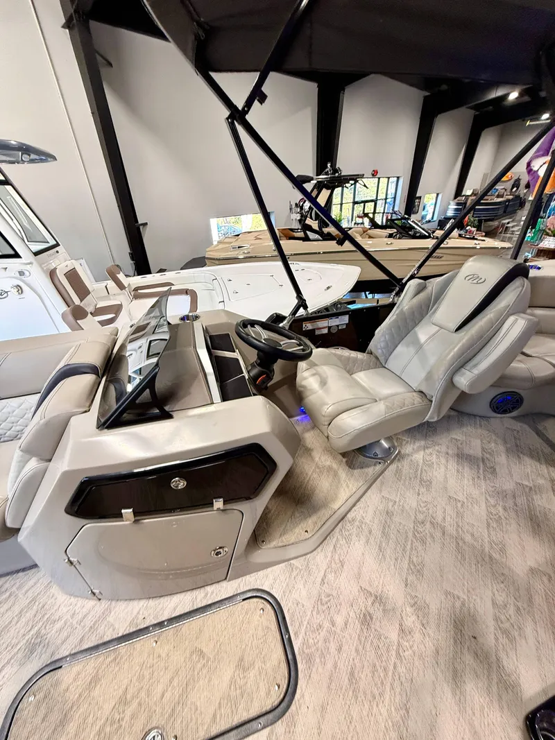 Slide: The Image of 2019 Manitou 25 SES Platinum boat interior with luxurious seating and modern dashboard. - 5