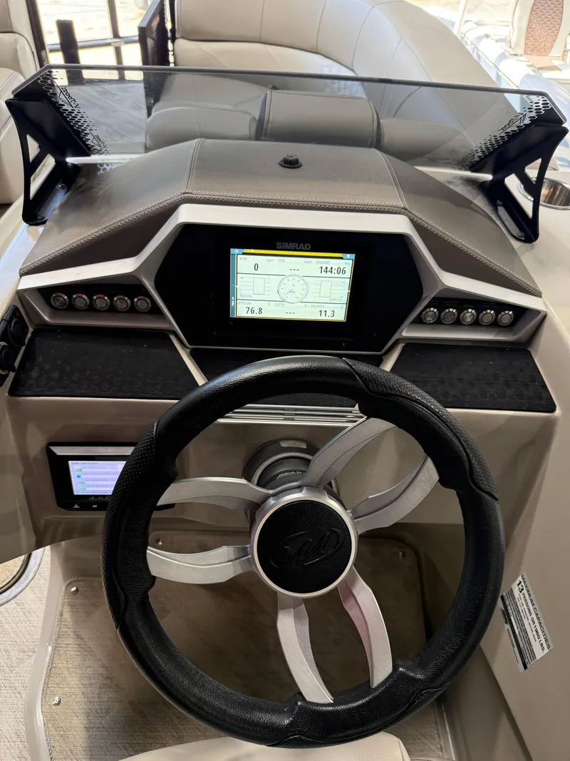 Slide: The Image of 2019 Manitou 25 SES Platinum boat dashboard with steering wheel and digital display. - 6