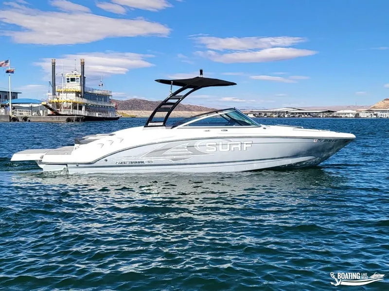 Slide: The Image of 2021 Chaparral 23 Surf boat on a sunny lake with a paddle steamer in the background. - 0