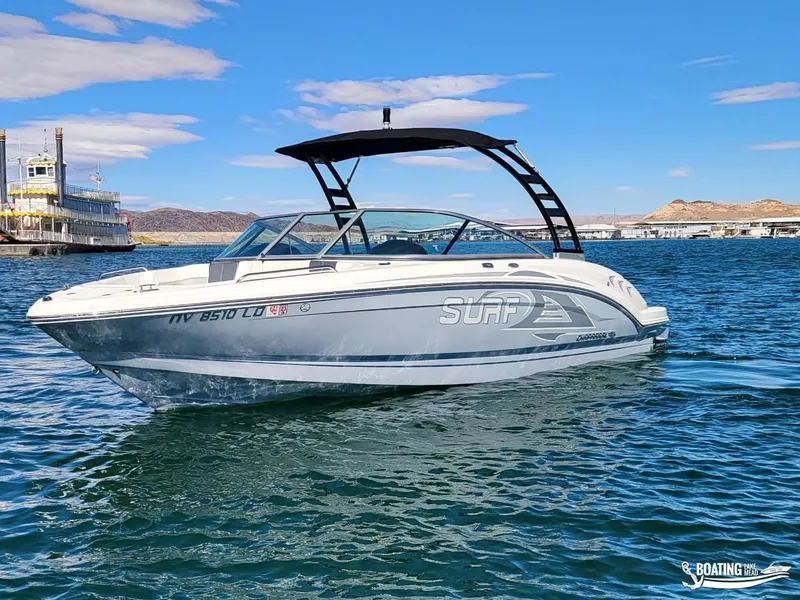 Slide: The Image of 2021 Chaparral 23 Surf boat on a sunny lake with distant hills. - 1