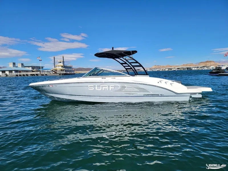 Slide: The Image of 2021 Chaparral 23 Surf boat on water, clear sky, marina background. - 5