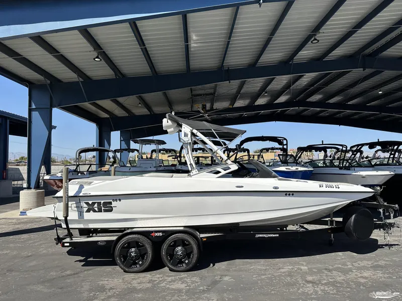 Slide: The Image of 2012 Axis A22 boat under a metal canopy, parked on a trailer. - 0
