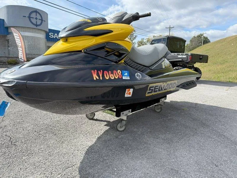 Slide: The Image of 2007 Sea-Doo RXP 215 jet ski, black and yellow, parked on pavement. - 2