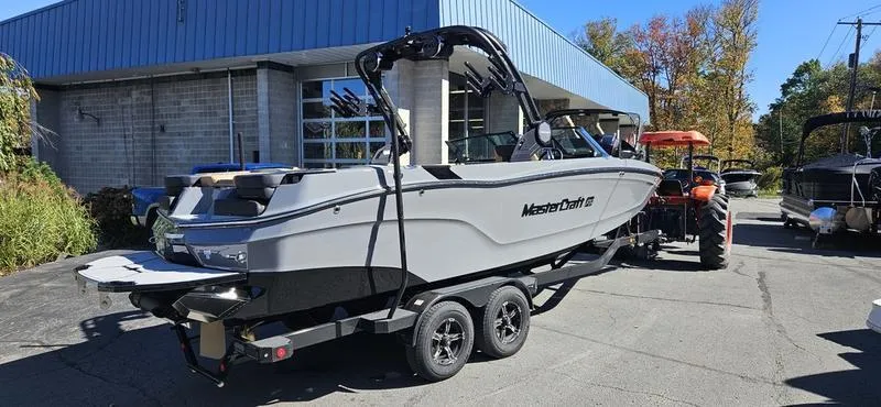 Slide: The Image of 2025 MasterCraft XT24 boat on trailer outside a building. - 1