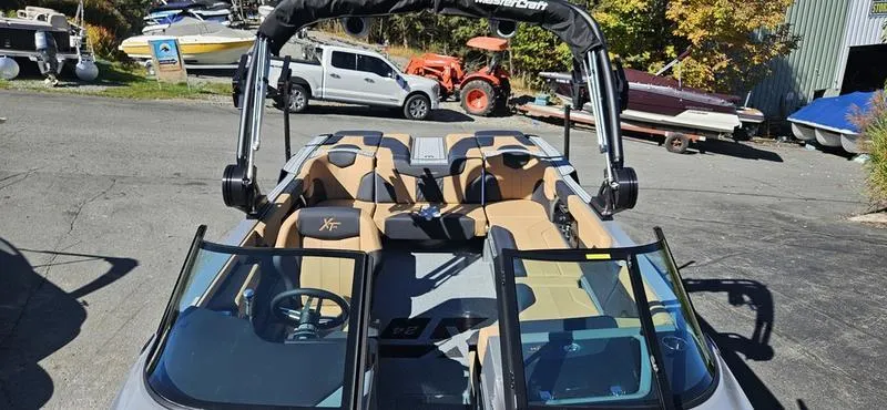 Slide: The Image of 2025 MasterCraft XT24 boat with open seating and sleek design in a marina setting. - 11