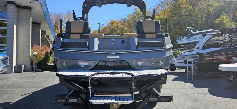 Slide: The Image of 2025 MasterCraft XT24 boat, rear view, parked outdoors with trees in the background. - 3