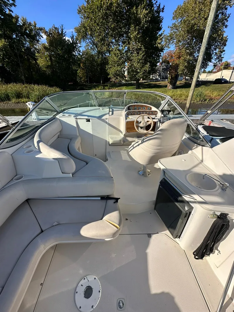 Slide: The Image of 1997 Regal 292 Commodore boat interior with seating and steering wheel, surrounded by trees. - 11