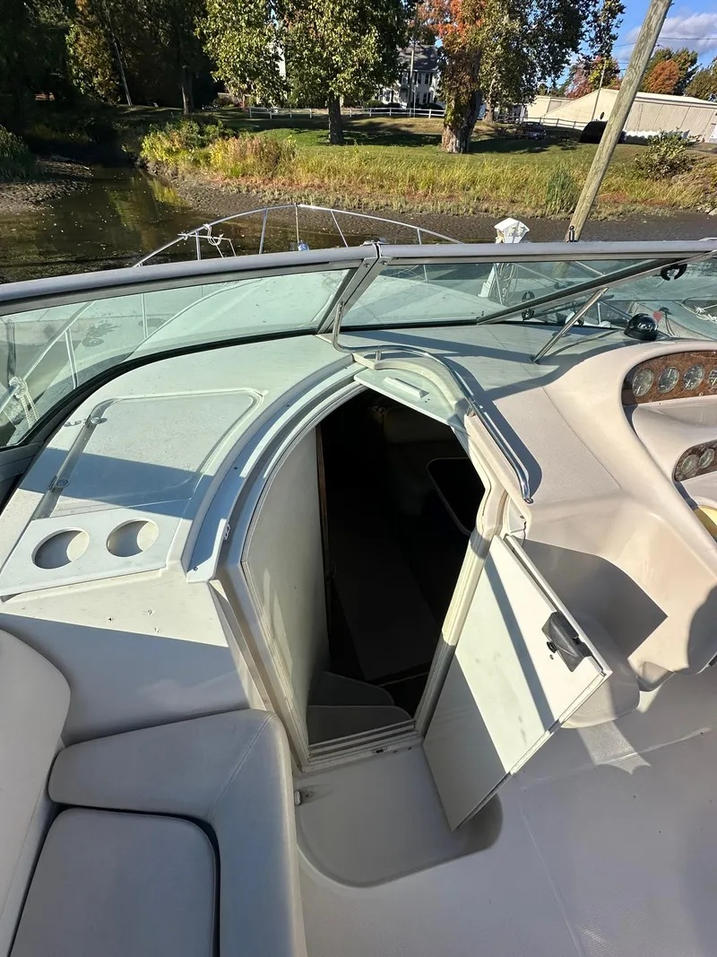 Slide: The Image of 1997 Regal 292 Commodore boat interior with open cabin door, docked by a scenic shoreline. - 15