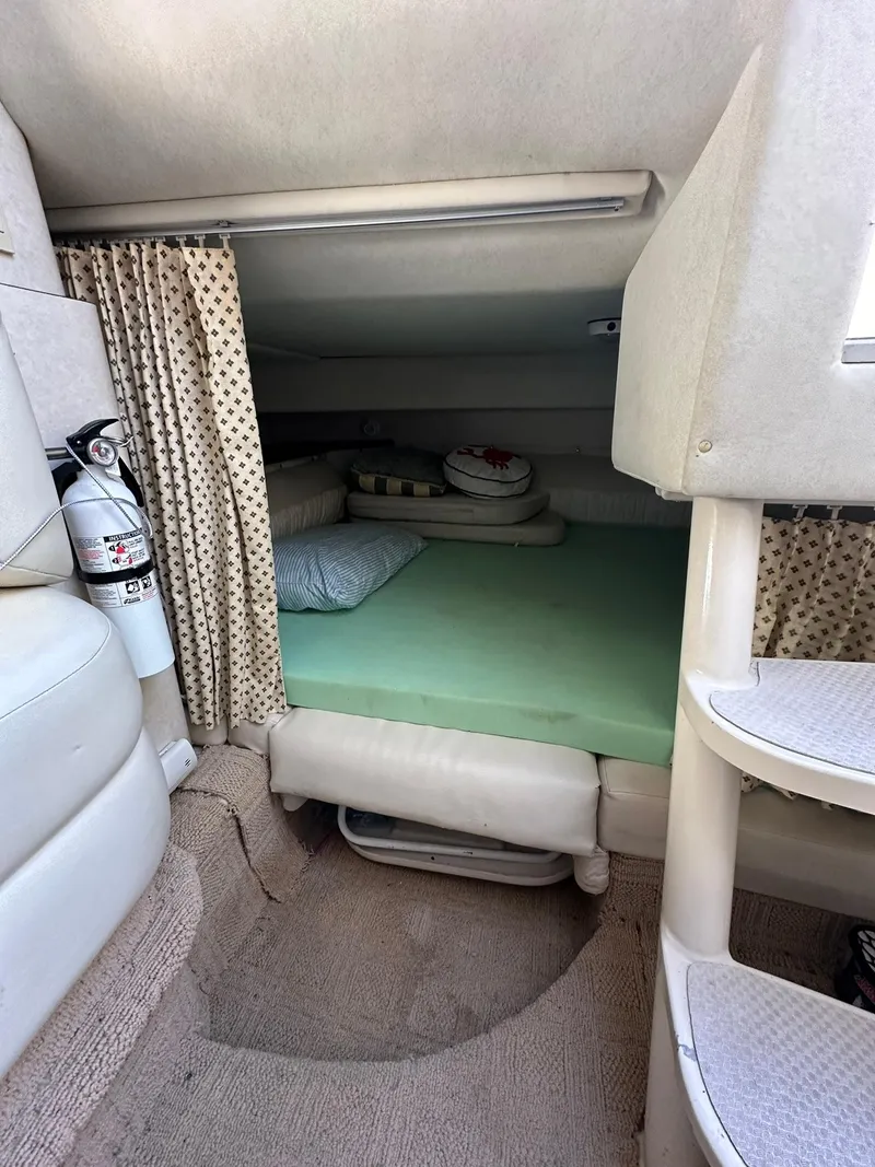 Slide: The Image of 1997 Regal 292 Commodore cabin interior with bed, fire extinguisher, and patterned curtains. - 22