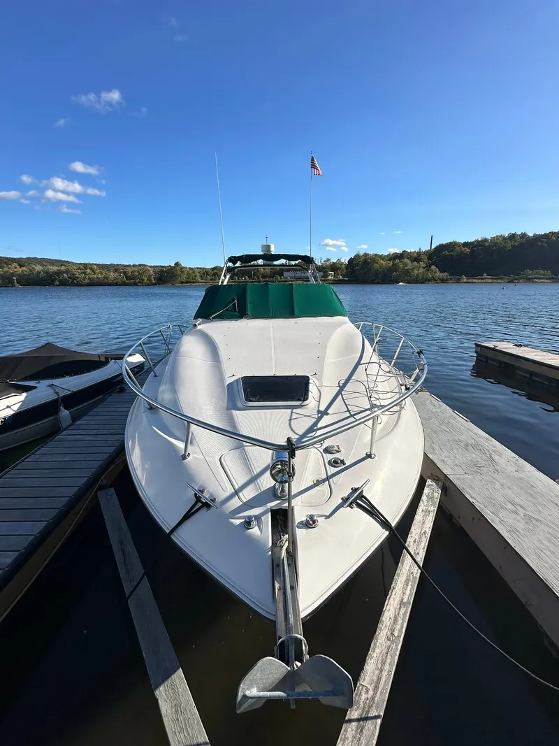 Slide: The Image of 1997 Regal 292 Commodore boat docked on a serene lake under a clear blue sky. - 3