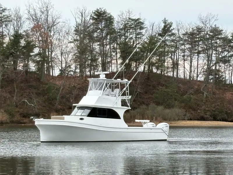 Slide: The Image of 2023 Millennium Marine NuWave Walkaround boat on a calm lake with trees in the background. - 12