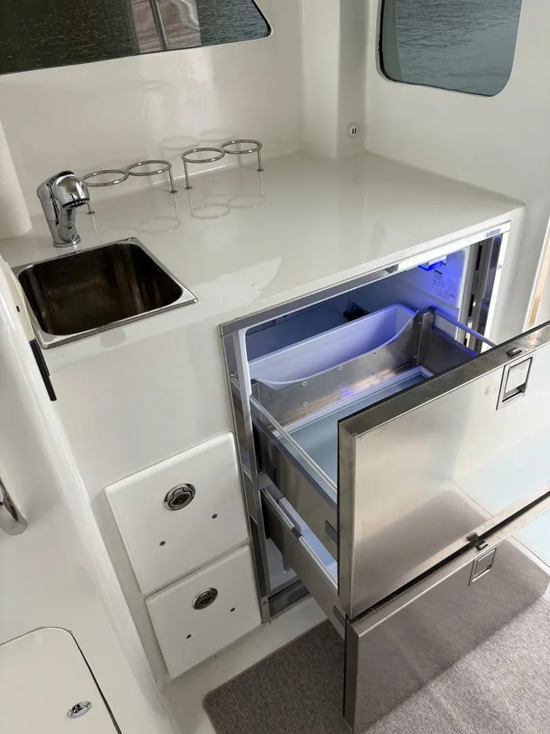 Slide: The Image of 2023 Millennium Marine NuWave Walkaround boat kitchen with sink and open refrigerator. - 19