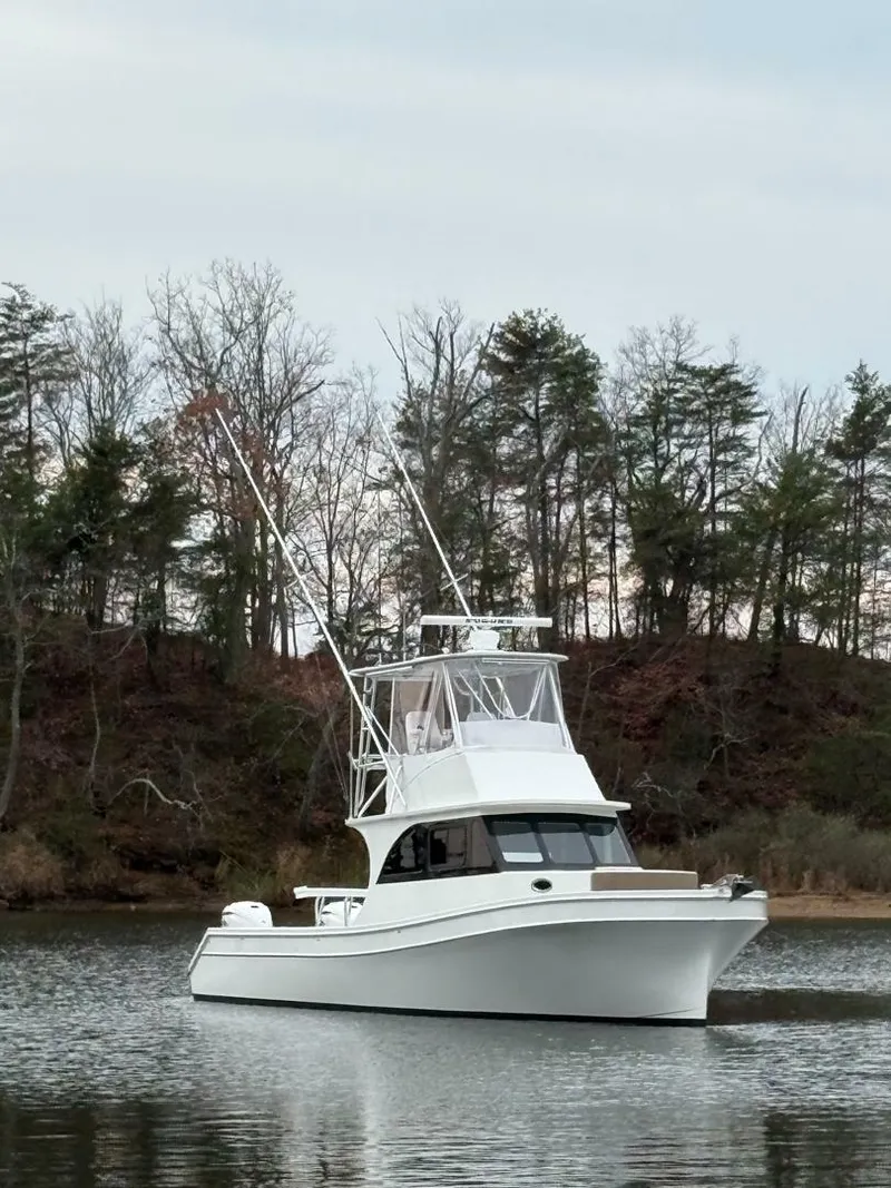 Slide: The Image of 2023 Millennium Marine NuWave Walkaround boat on calm water with trees in the background. - 21