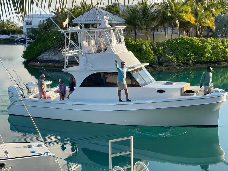 Slide: The Image of 2023 Millennium Marine NuWave Walkaround boat in tropical marina with people on deck. - 24