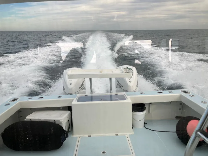 Slide: The Image of 2023 Millennium Marine NuWave Walkaround boat cruising on open water, leaving a wake trail. - 3