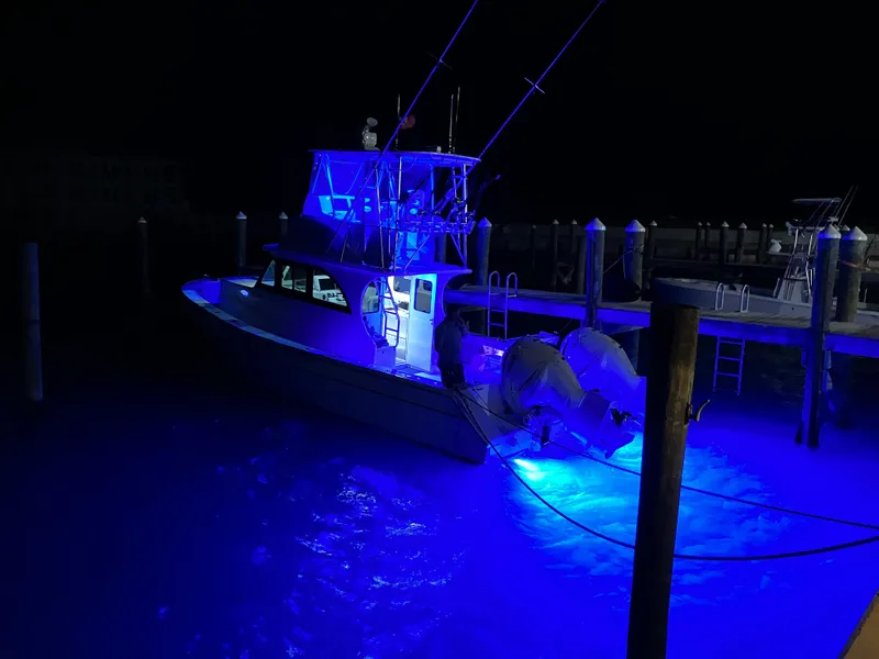 Slide: The Image of 2023 Millennium Marine NuWave Walkaround boat illuminated with blue lights at night. - 36