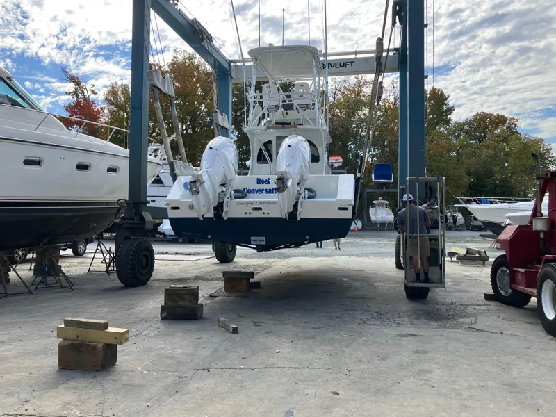 Slide: The Image of 2023 Millennium Marine NuWave Walkaround boat in a shipyard lift, surrounded by other vessels. - 38