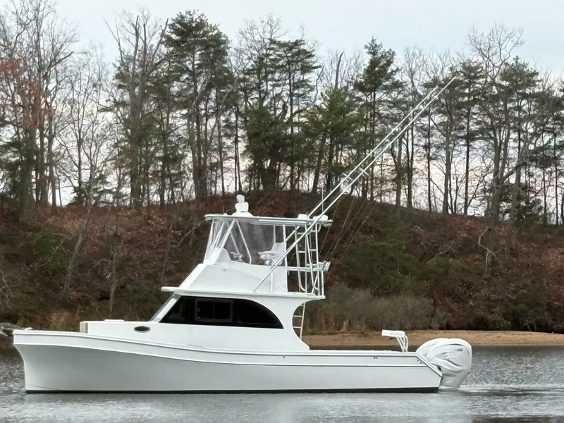 Slide: The Image of 2023 Millennium Marine NuWave Walkaround boat on a calm lake with trees in the background. - 4