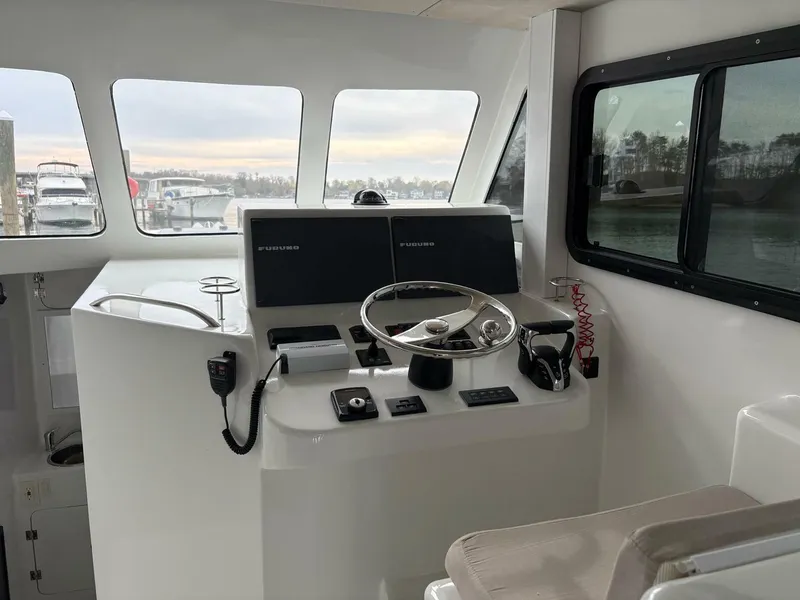Slide: The Image of 2023 Millennium Marine NuWave Walkaround boat cockpit with steering wheel and navigation screens. - 7