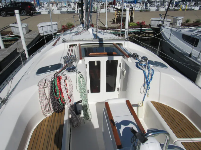 Slide: The Image of 1999 Beneteau 381 sailboat cockpit with ropes and wooden seating at a marina. - 2