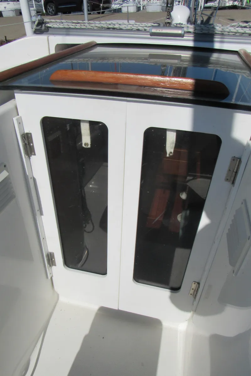 Slide: The Image of 1999 Beneteau 381 sailboat cockpit with glass-paneled doors and wooden handrail. - 27