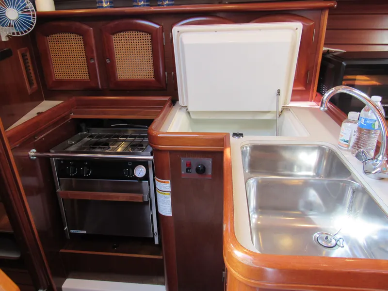 Slide: The Image of 1999 Beneteau 381 yacht kitchen with stove, sink, and storage cabinets. - 8
