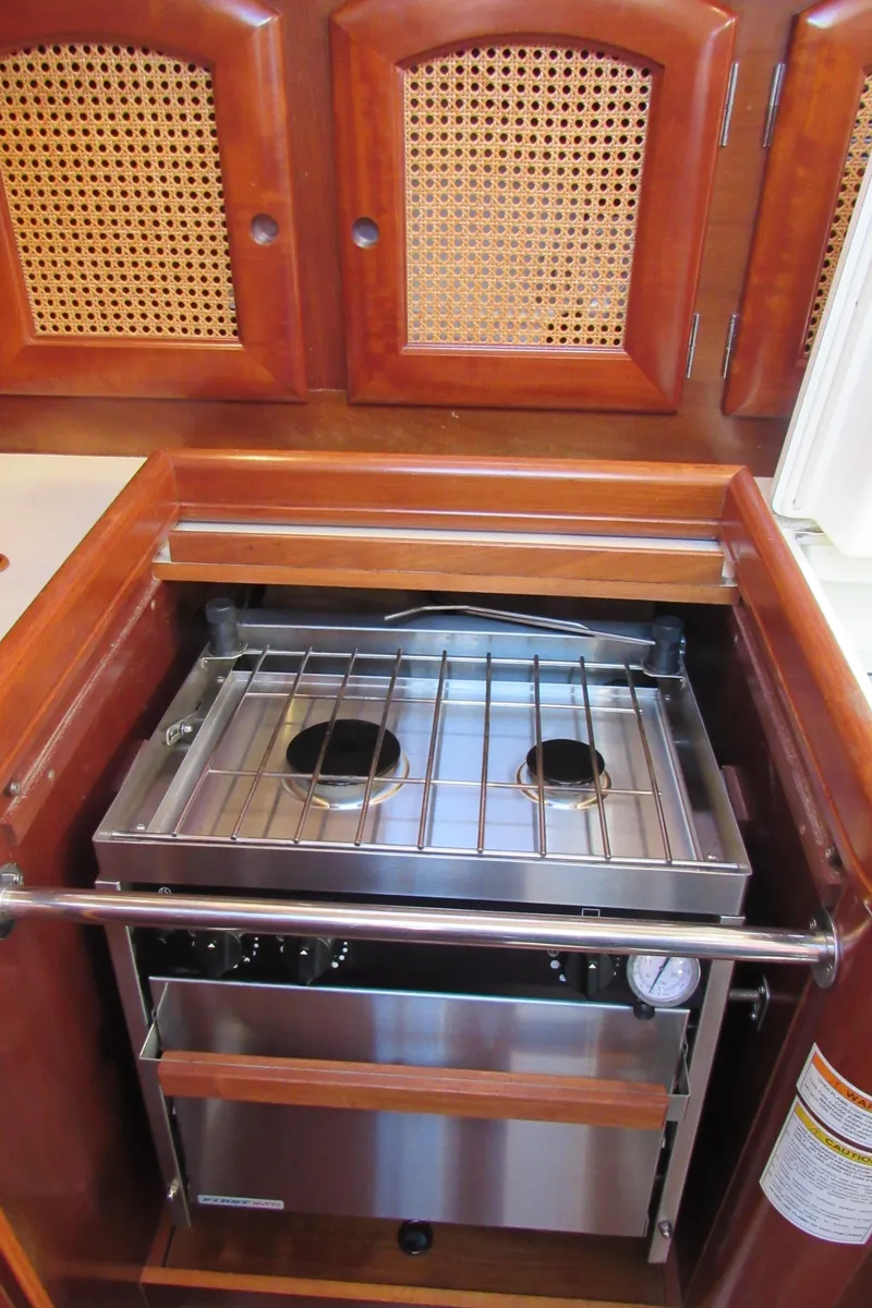 Slide: The Image of 1999 Beneteau 381 yacht kitchen with a compact stainless steel stove and wooden cabinetry. - 9