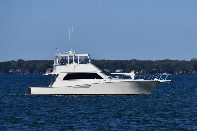 Slide: The Image of 1990 Viking 53 Convertible yacht cruising on a calm lake with distant shoreline. - 0