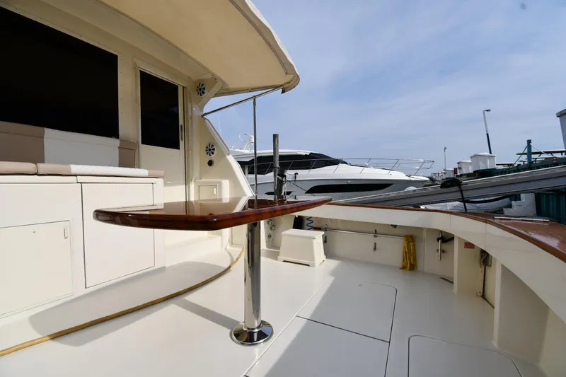 Slide: The Image of 1990 Viking 53 Convertible yacht deck with seating and table, docked under clear skies. - 13
