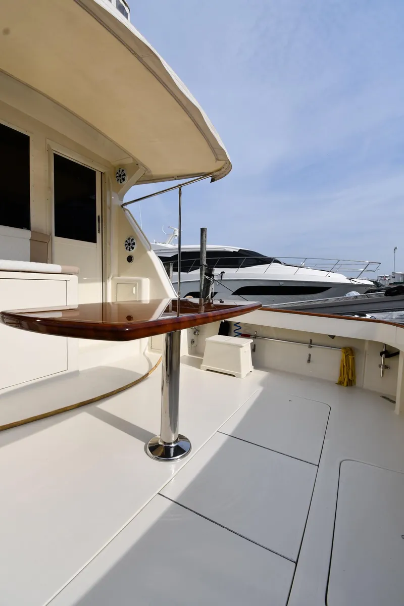Slide: The Image of 1990 Viking 53 Convertible yacht deck with polished wood table and marina view. - 14