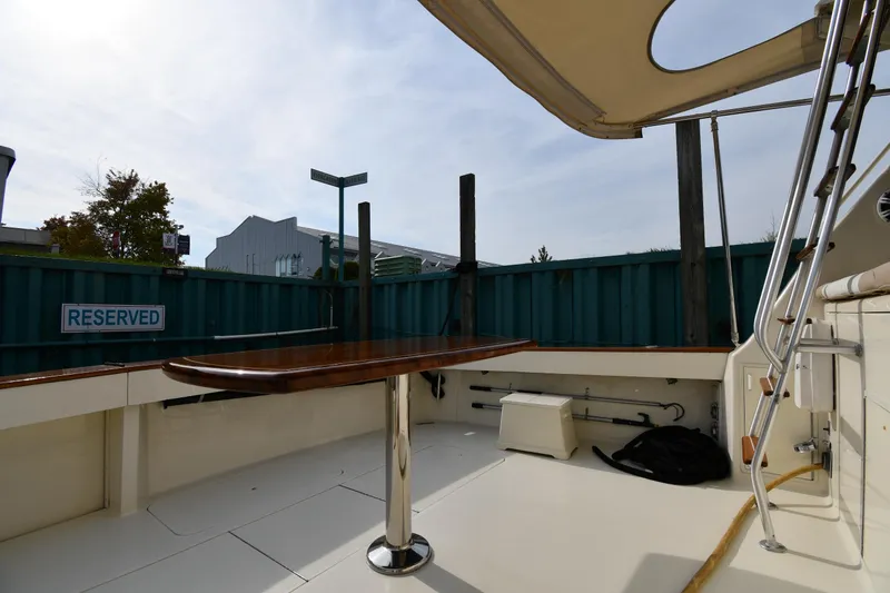 Slide: The Image of 1990 Viking 53 Convertible boat deck with table, reserved sign, and canopy. - 17
