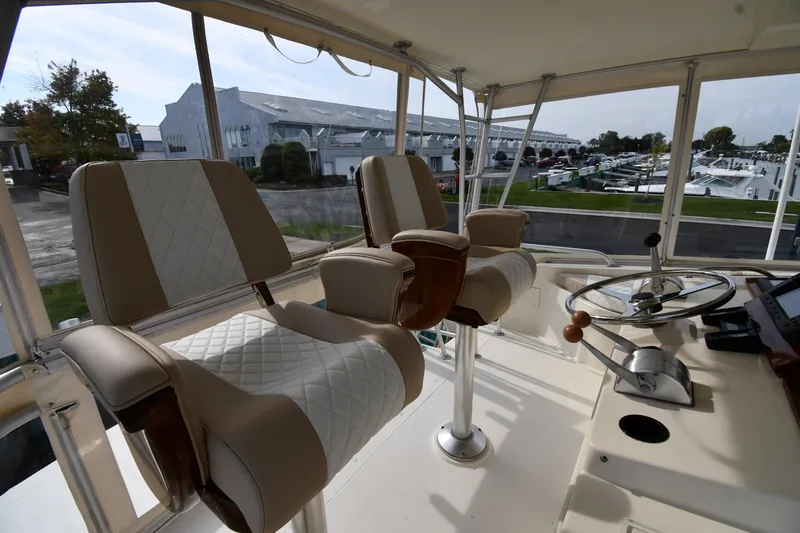 Slide: The Image of 1990 Viking 53 Convertible yacht helm with cushioned seats and steering wheel, marina view. - 27
