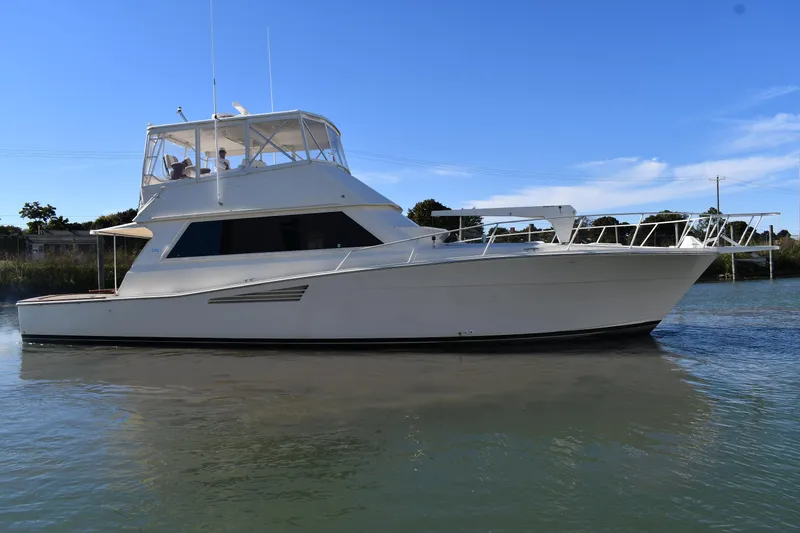 Slide: The Image of 1990 Viking 53 Convertible yacht on calm water under clear blue sky. - 3