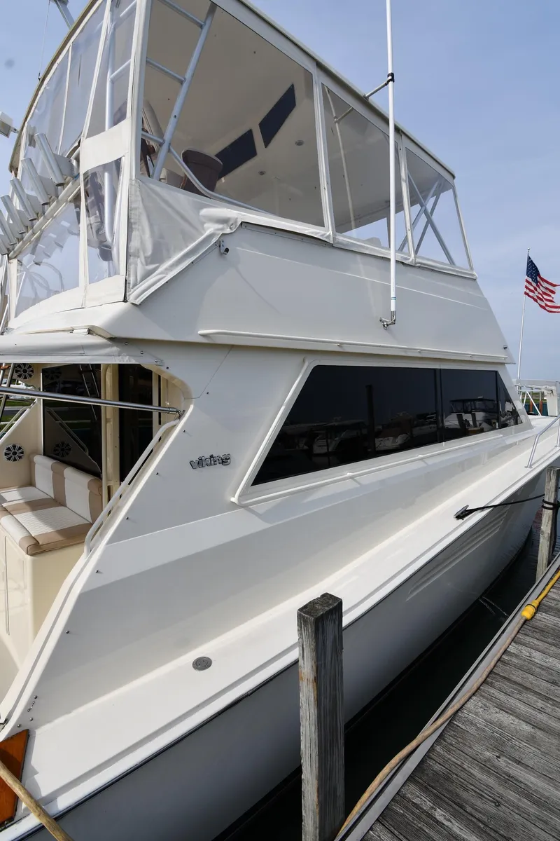 Slide: The Image of 1990 Viking 53 Convertible yacht docked, featuring sleek design and spacious upper deck. - 7