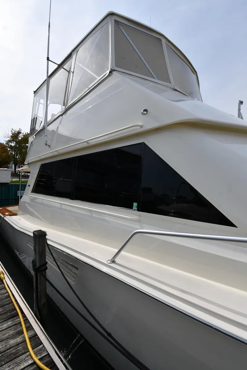 Slide: The Image of 1990 Viking 53 Convertible yacht docked, showcasing sleek design and spacious upper deck. - 8