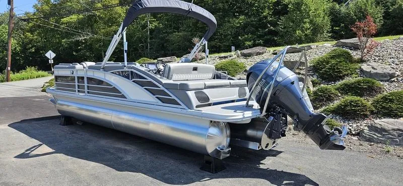 Slide: The Image of 2025 Bennington 23 RSB pontoon boat with outboard motor, parked on a sunny day. - 2