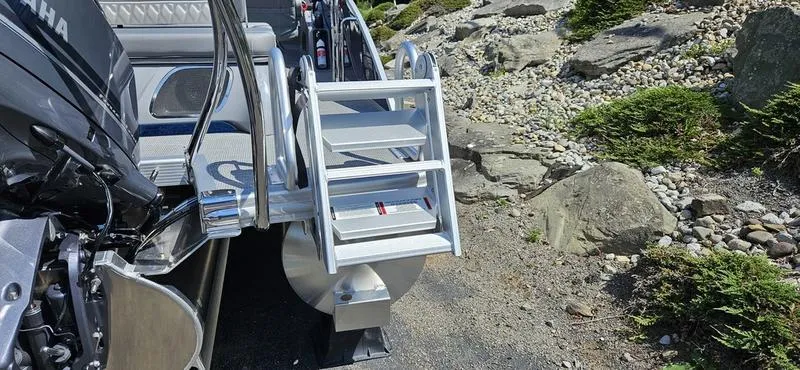 Slide: The Image of 2025 Bennington 23 RSB boat with ladder and Yamaha engine, parked on rocky terrain. - 3