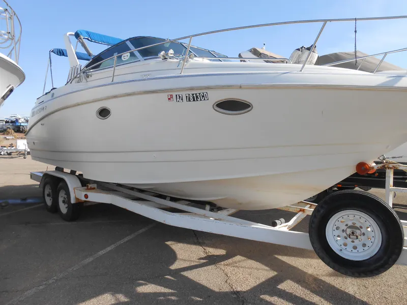 The Image of 1995 Larson 280 Cabrio boat on trailer, white hull, parked outdoors. - 0
