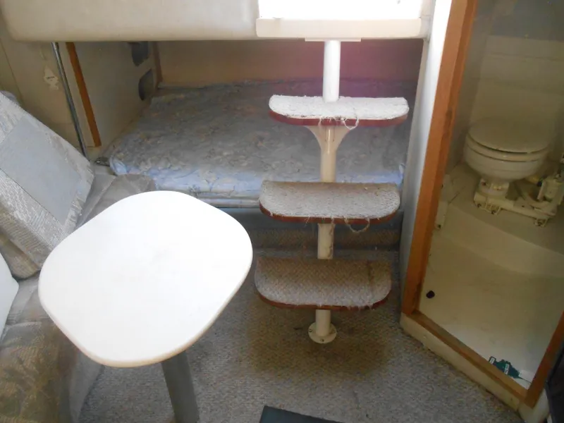 Slide: The Image of Interior of a 1995 Larson 280 Cabrio boat with seating, table, and compact bathroom. - 3