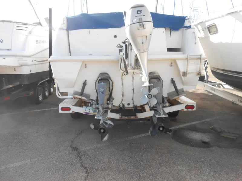 Slide: The Image of 1995 Larson 280 Cabrio boat with dual outboard motors in a marina parking lot. - 4