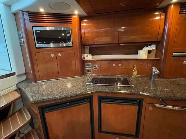 Slide: The Image of 2005 Sea Ray 390 Sundancer kitchen with wood cabinetry and modern appliances. - 21