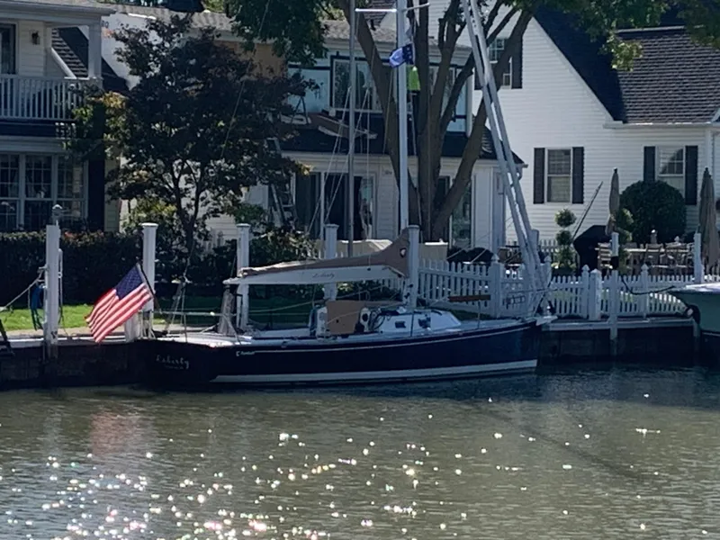 Slide: The Image of Sailboat Tartan Fantail 2022 docked by waterfront homes with American flag. - 15