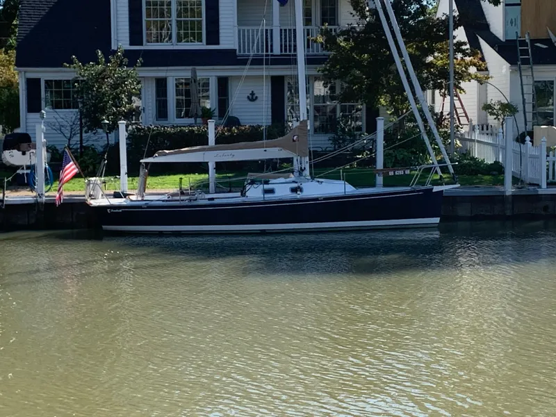 Slide: The Image of 2022 Tartan Fantail sailboat docked by a waterfront house with an American flag. - 17