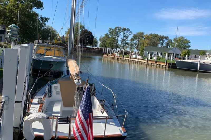 Slide: The Image of Sailboat docked in a serene marina, Tartan Fantail 2022 model, with American flag displayed. - 30